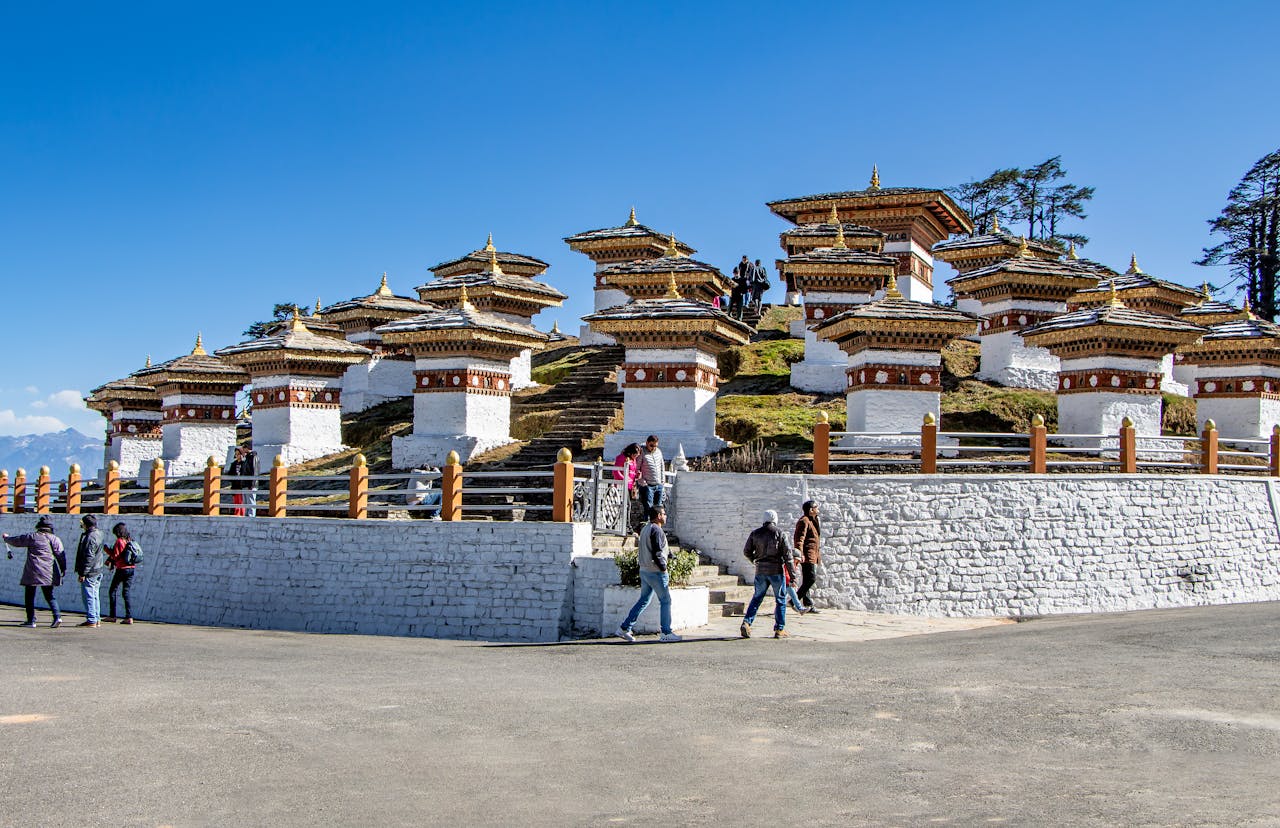 why-choose-us Scenic view of Dochula Pass featuring Druk Wangyal Chortens in Bhutan with tourists exploring.